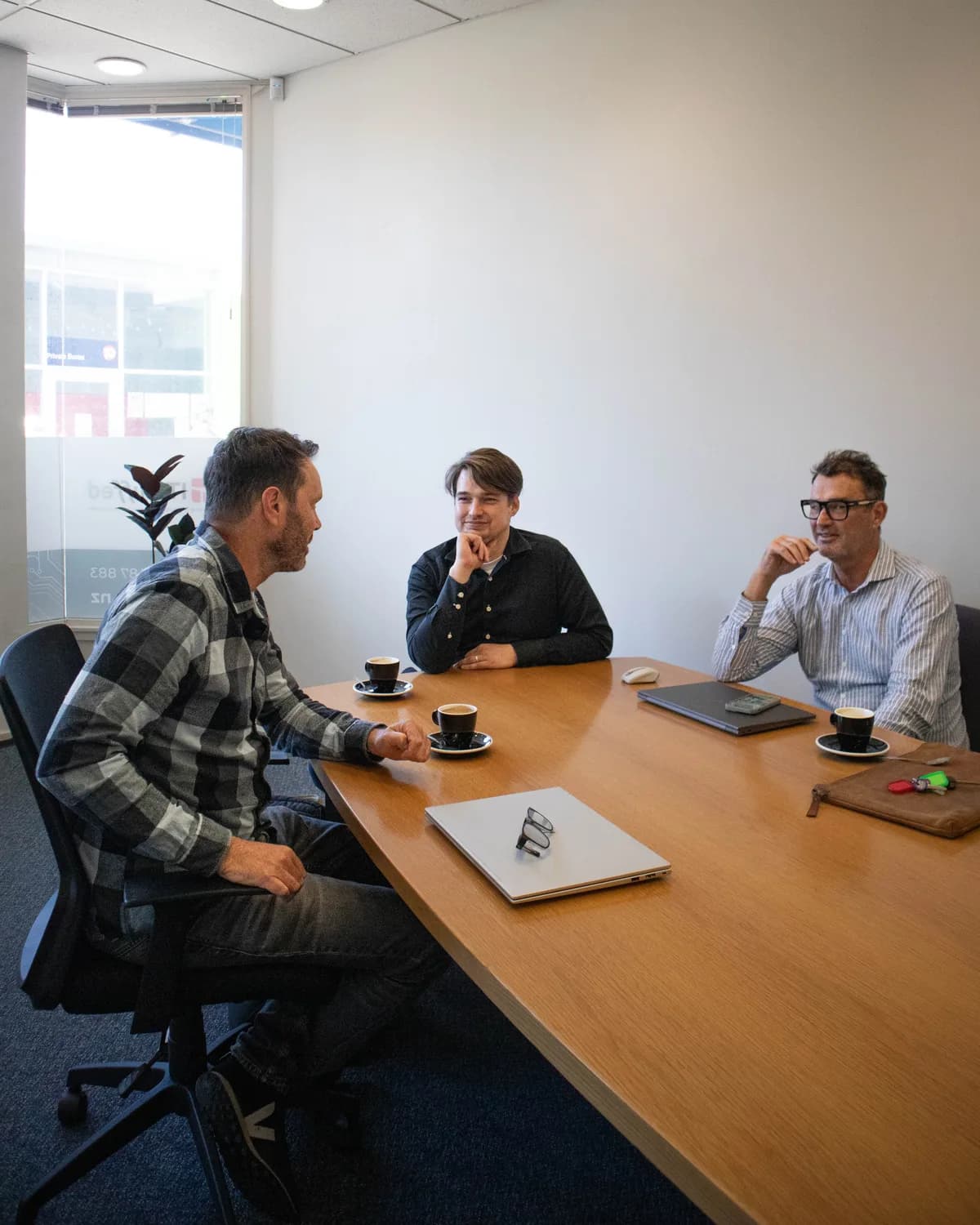 Three people talking around a meeting table in the ITstuffed office